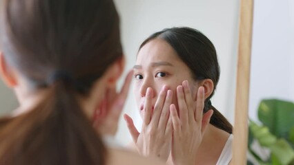 Young Asian woman checking spot on her face and skin problem in mirror