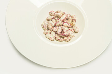 Frijoles dentro de un plato blanco sobre un fondo blanco. Vista superior y de cerca. Copy space