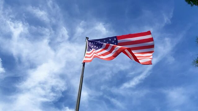 Flag of the United States of America waving in the blue sky in slow motion. USA. American flag. US flag.