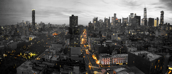 Yellow lights of the New York City skyline shining against a black and white cityscape in Lower Manhattan NYC