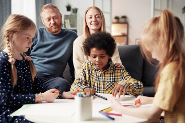 Group of children drawing pictures at table for their parents during leisure time at home