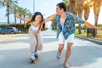 Young diverse couple with skateboard and longboard having fun outdoors.