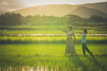 Naklejka na ściany i meble Mother and daughter travel in rice field on sunset