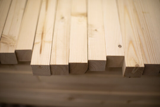 Boards in stock. Wooden blanks. Bars made of wood of light color.