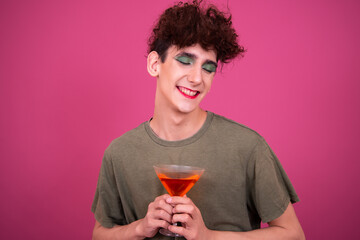 Drag queen drinks a cocktail. Funny guy in make-up.	