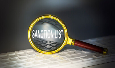 SANCTIONS LIST word concept on a magnifier on the keyboard