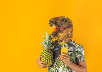 Man wearing dinosaur animal head mask holding pineapple fruit and drinking cocktail or juice...