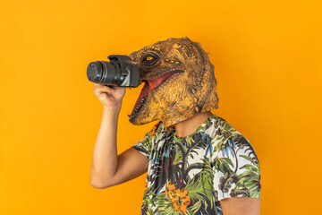 Man taking picture with professional camera wearing animal head mask isolated on yellow background