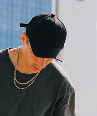 guy in a black cap and gray t-shirt with a gold chain around his neck