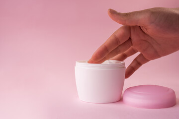 Hand taking cream from a skin cream bottle for women