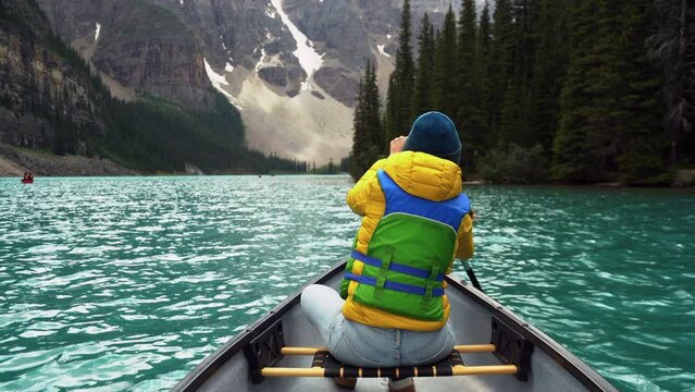 Tourist paddling a canoe on Moraine Lake during summer in Banff National Park, Alberta, Canada.