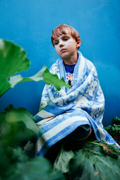 sad child sitting on the street in a blanket