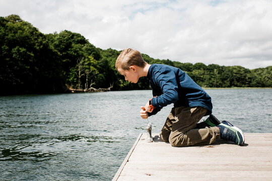 young boy with a fishing crabbing net looking over the dock