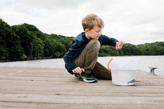boy happily holding a crab that he caught whilst fishing on the dock