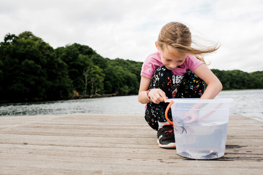girl holding a crab that she caught whilst fishing on the dock