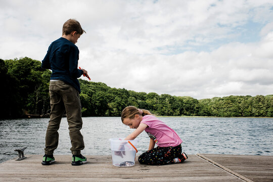 brother and sister crabbing together on a dock in the countryside