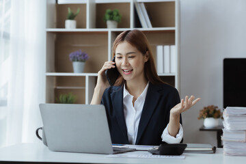 Asian woman talking on the phone, she is a salesperson in a startup company, she is calling customers to sell products and promotions. Concept of selling products through telephone channels.