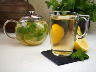 A cup of green tea with lemon and mint. Teapot.