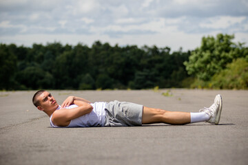 Obraz premium A Nineteen Year Old Teenage Boy Doing Leg Raises In A Public Park