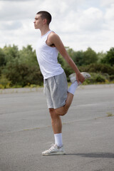 Fototapeta na wymiar A Nineteen Year Old Teenage Boy Stretching In A Public Park