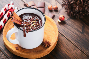 Hot chocolate. Homemade spicy hot chocolate with cinnamon, crushed hazelnut in enamel mug on old wooden background. Cozy seasonal holidays.