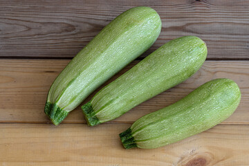 three green zucchini on a table of rough wooden boards