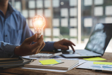 Businessman's hand holding a light bulb that glows like an idea for work