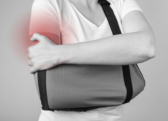 Woman wearing sling to support injured shoulder with red spot. Arm trauma, injury, acromion...