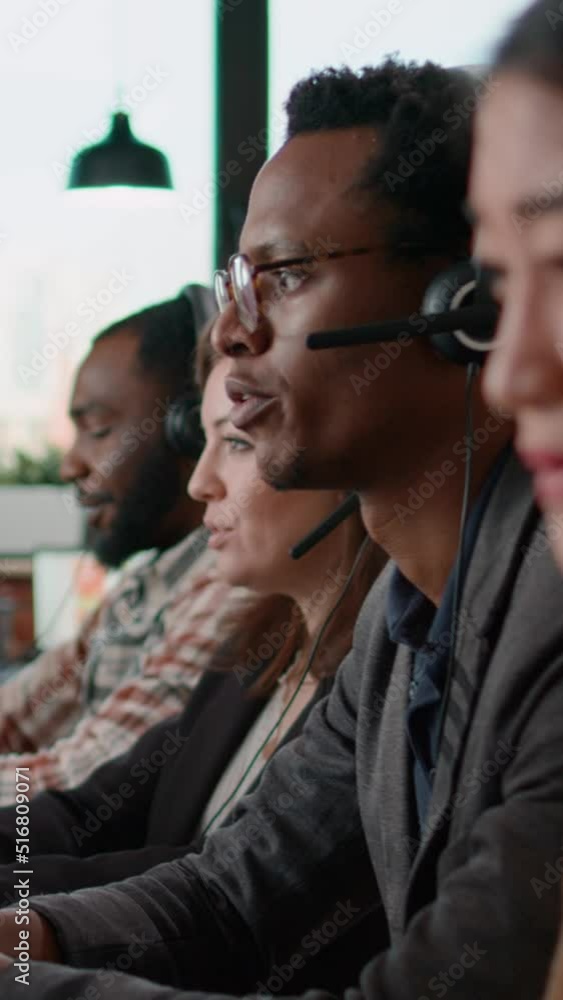 Poster vertical video: helpline agents talking to clients on headset at call center job, using computer to 