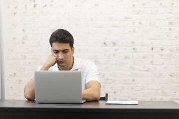 Young serious businessman working on laptop at home. Distant work concept