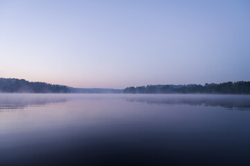 Fototapeta na wymiar Beautiful mystical landscape. Forest lake at twilight. Fog above calm water. Scenic nature.