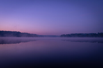 Fototapeta premium Beautiful mystical landscape. Forest lake at twilight. Fog above calm water. Scenic nature.