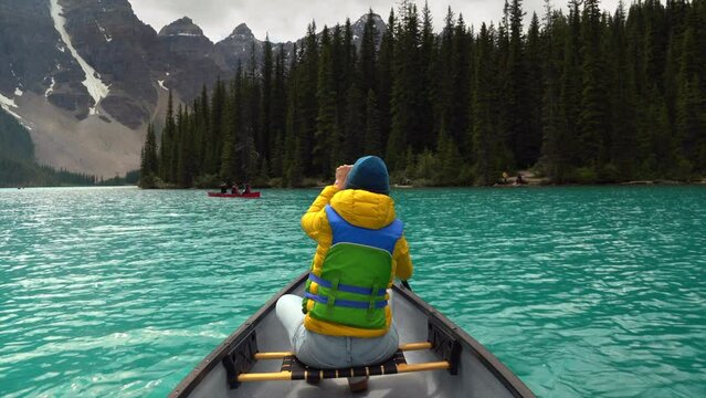 Tourist paddling a canoe on Moraine Lake during summer in Banff National Park, Alberta, Canada.
