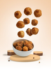 Homemade croquettes falling into a bowl isolated from the background with wooden geometric shapes