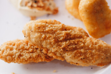 Close up of chicken nuggets in basket with parchment paper and chili tomato sauce on wooden background.