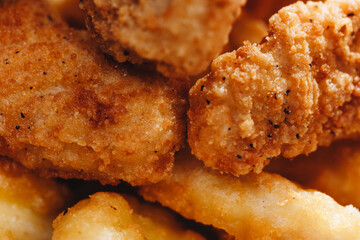 Close up of chicken nuggets in basket with parchment paper and chili tomato sauce on wooden background.