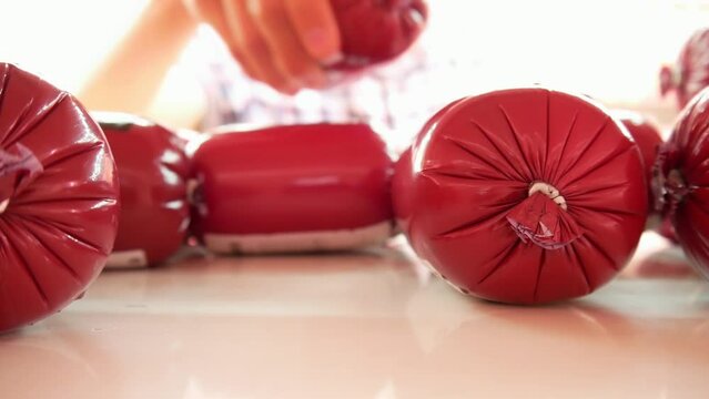Close-up of beautiful red sausages on a fridge shelf and a male buyer takes one