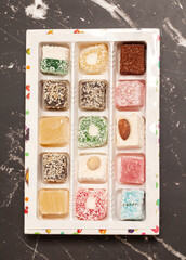 Cubes of traditional oriental sweets on a marble background, top view.