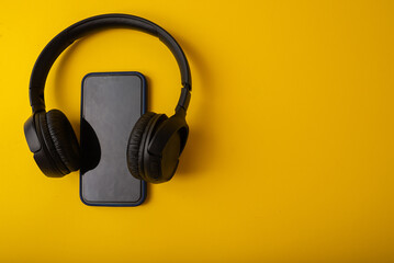 Headphones and phone on yellow background