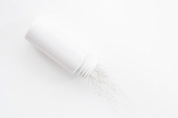 Fototapeta na wymiar Spilled white talcum powder in container. Skin care cosmetic
