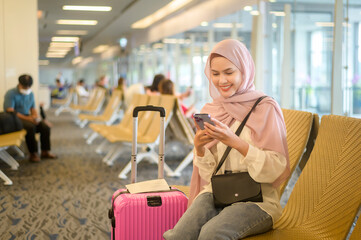 Young female muslim traveler carrying suitcases at the International airport, travel, holidays and...