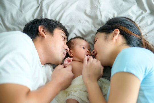 Smiling young mother and father with a new born baby, family and love concept