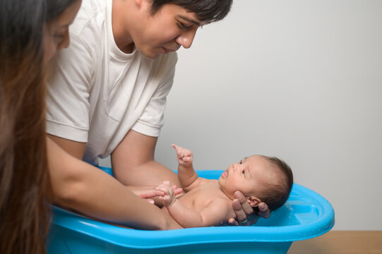 New born having a bath by happy mother and father, family and love concept