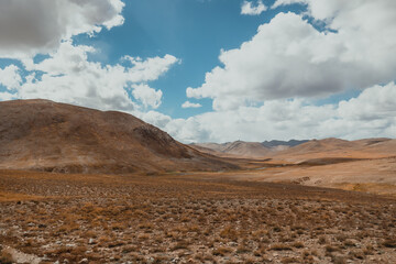 large hill in Deosai National Park on a sunny summer day in Pakistan with mountain range on horizon