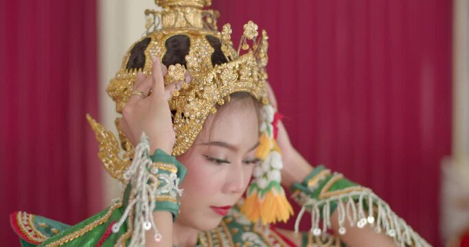 An Asian woman slowly wears a jada on her head. There is a flower attached to the side of the Chada in Thai people called Dok Mai Tard and the hanging flower in Thai people is called uba.