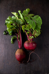 two garden beets with tops on a stone brown table, dark photo