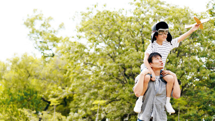 Lifestyle Asian family Father and son sat on his shoulders and run in  park. Paper plane as a toy...
