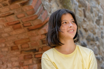 Portrait of a young girl on the background of a stone wall with an arch.