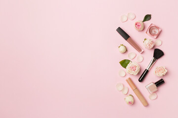 Makeup products with flowers on color background, top view