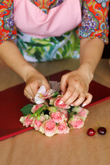 florist makes an unusual bouquet of roses and cherries